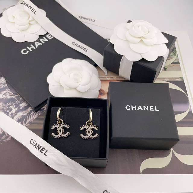 We offer a pair of gold hook earrings with black lace and white C studs, priced