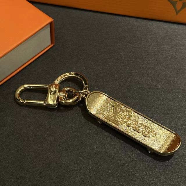 The Lvskate bag charm and keychain are crafted from shiny brass in the shape of