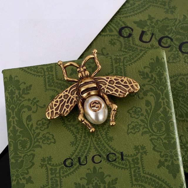 The Gucci Double G brooch, a signature element of the brand, uses the brand's i