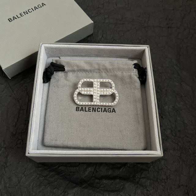 Balenciaga brooch, simple, elegant, and with a rich, high-end gold finish; looks