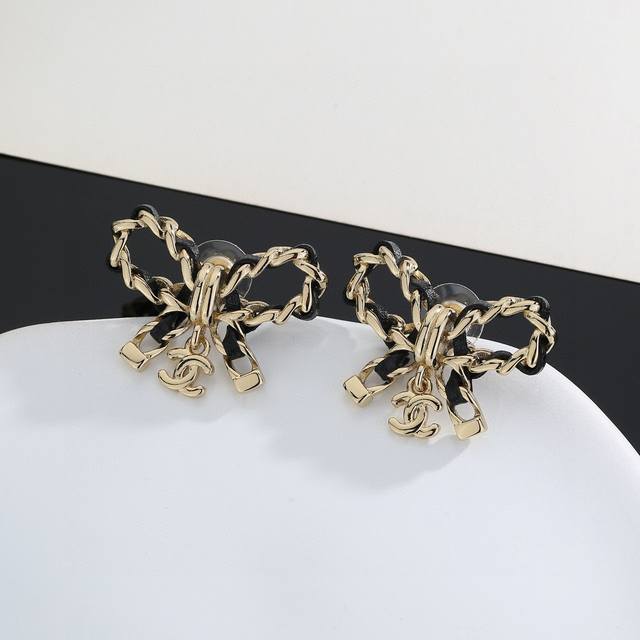Chanel's new bow-adorned black leather stud earrings, flattering the face shape.