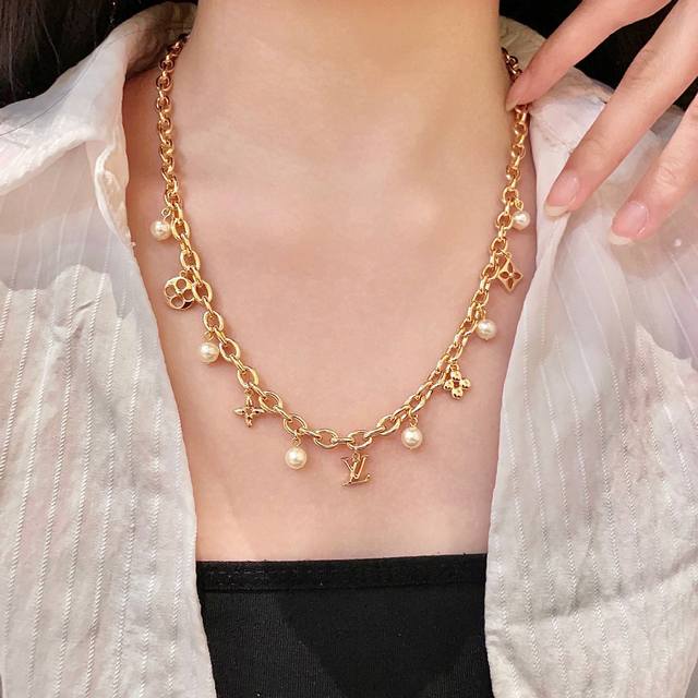 This Louis Vuitton pendant features a classic double-flower pattern and the LV b