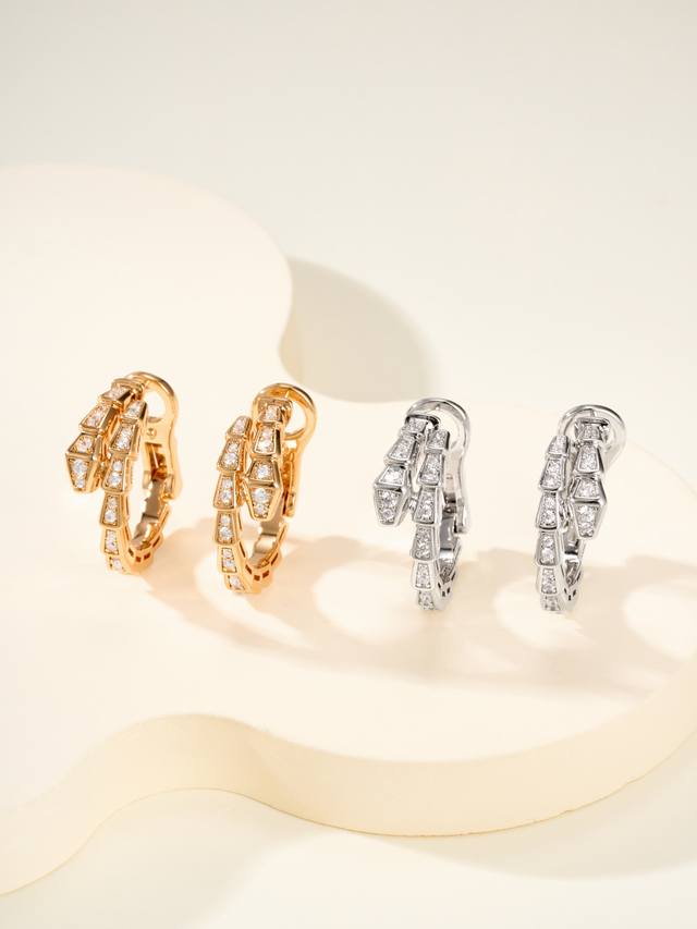 These snake-inspired earrings feature a unique, winding design. Fully set with d