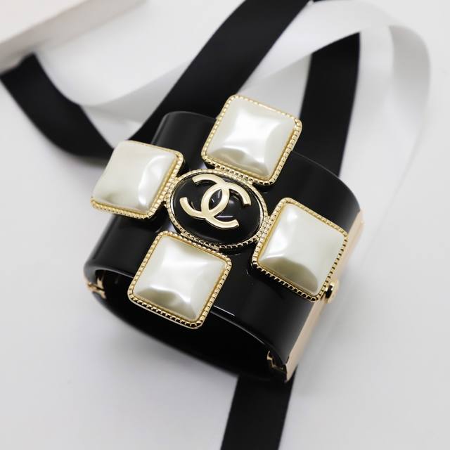 Ch Nel Bangle: A wide, European-style cross-shaped acrylic bangle with a clasp.